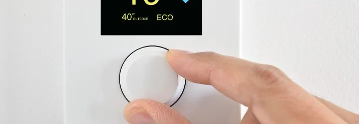 Person stellt Temperatur an Thermostat ein